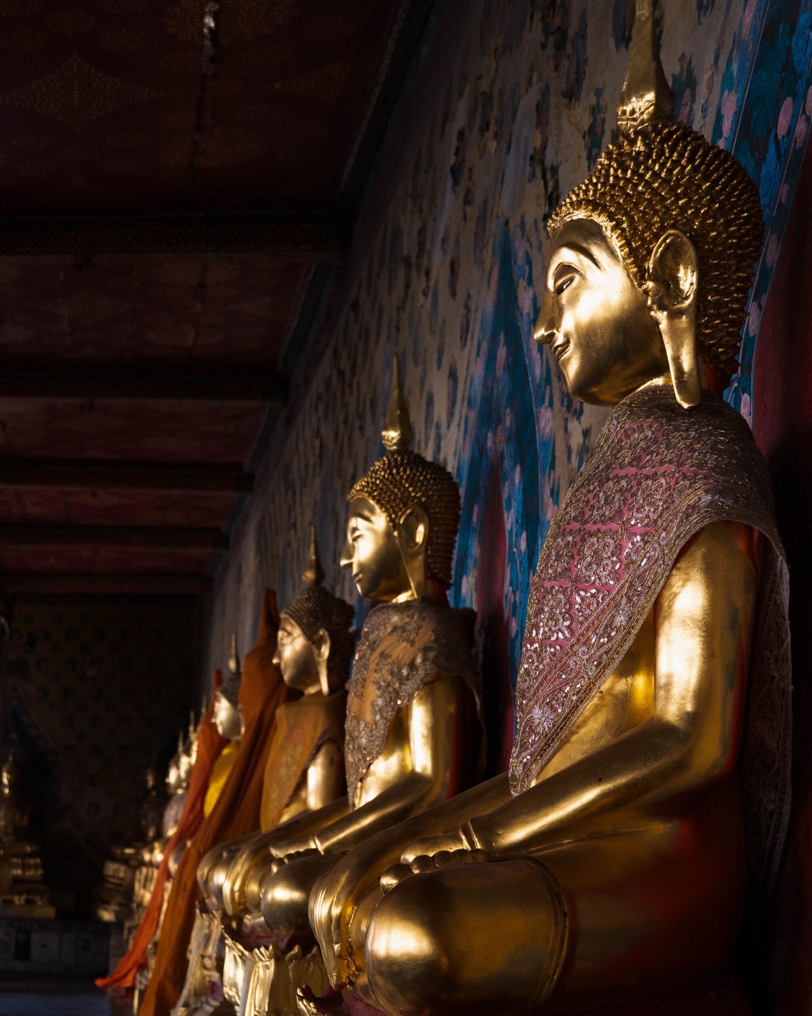 Rząd złotych posągów Buddy w krużganku Wat Arun w Bangkoku – symbol ciszy i skupienia w sercu świątyni