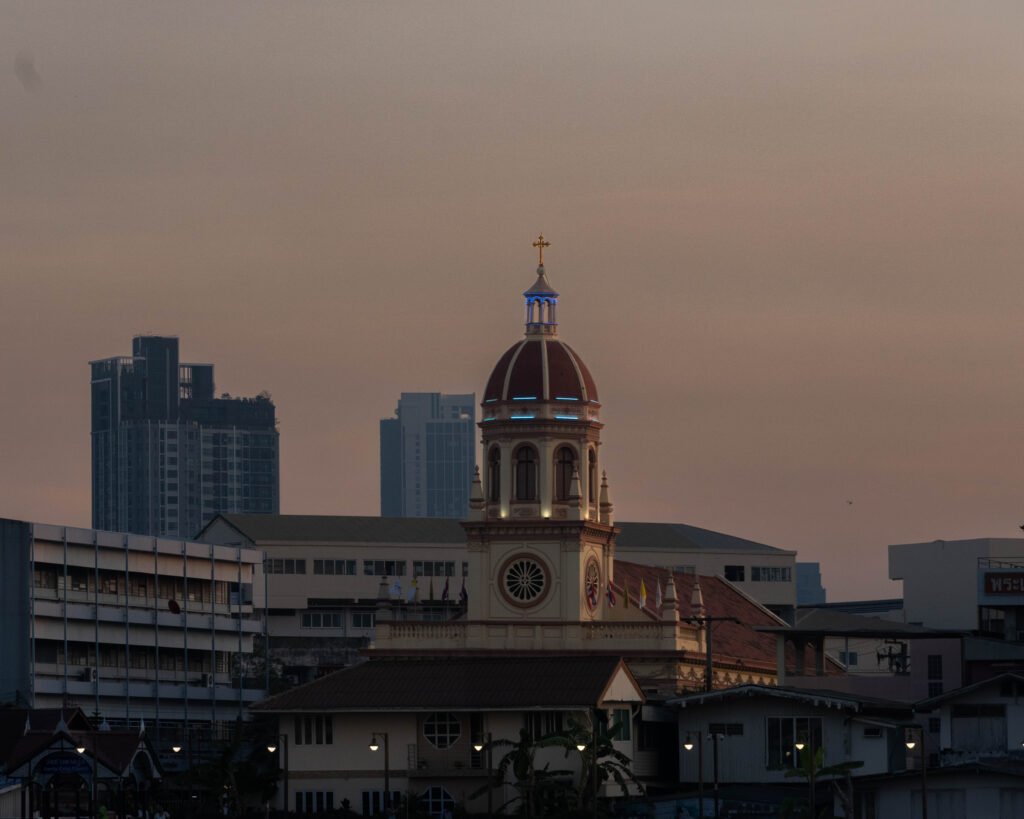 Widok na kościół Santa Cruz w Bangkoku z pokładu statku podczas rejsu rzeką Chao Phraya o zachodzie słońca.