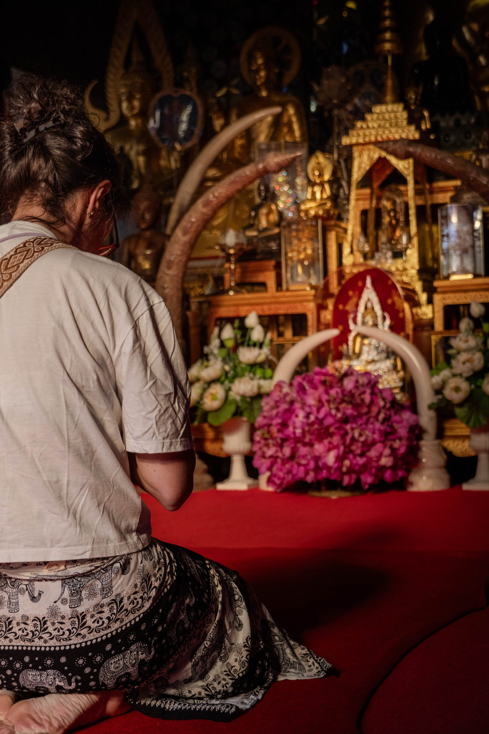 Tajka modląca się w świątyni Wat Doi Suthep, na wzgórzu w Chiang Mai. Zdjęcie przedstawia głębokie skupienie, doskonale oddając atmosferę tego historycznego miejsca kultu w Tajlandii.