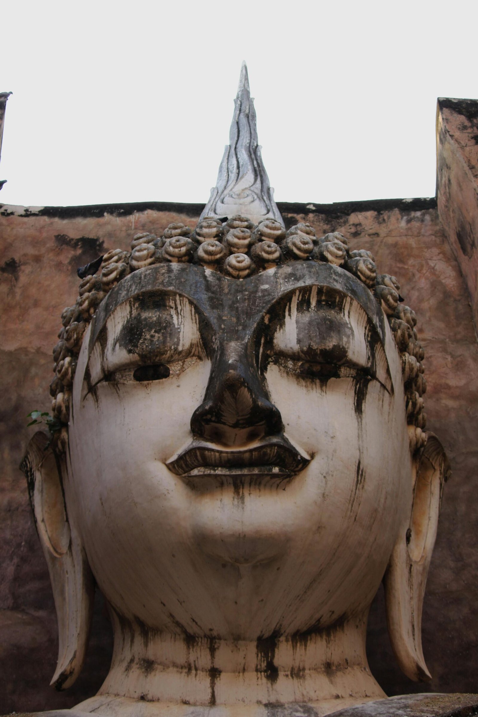 Close-up of a historic Buddha statue at Wat Si Chum, Sukhothai, Thailand, showcasing intricate artistry and spiritual significance.