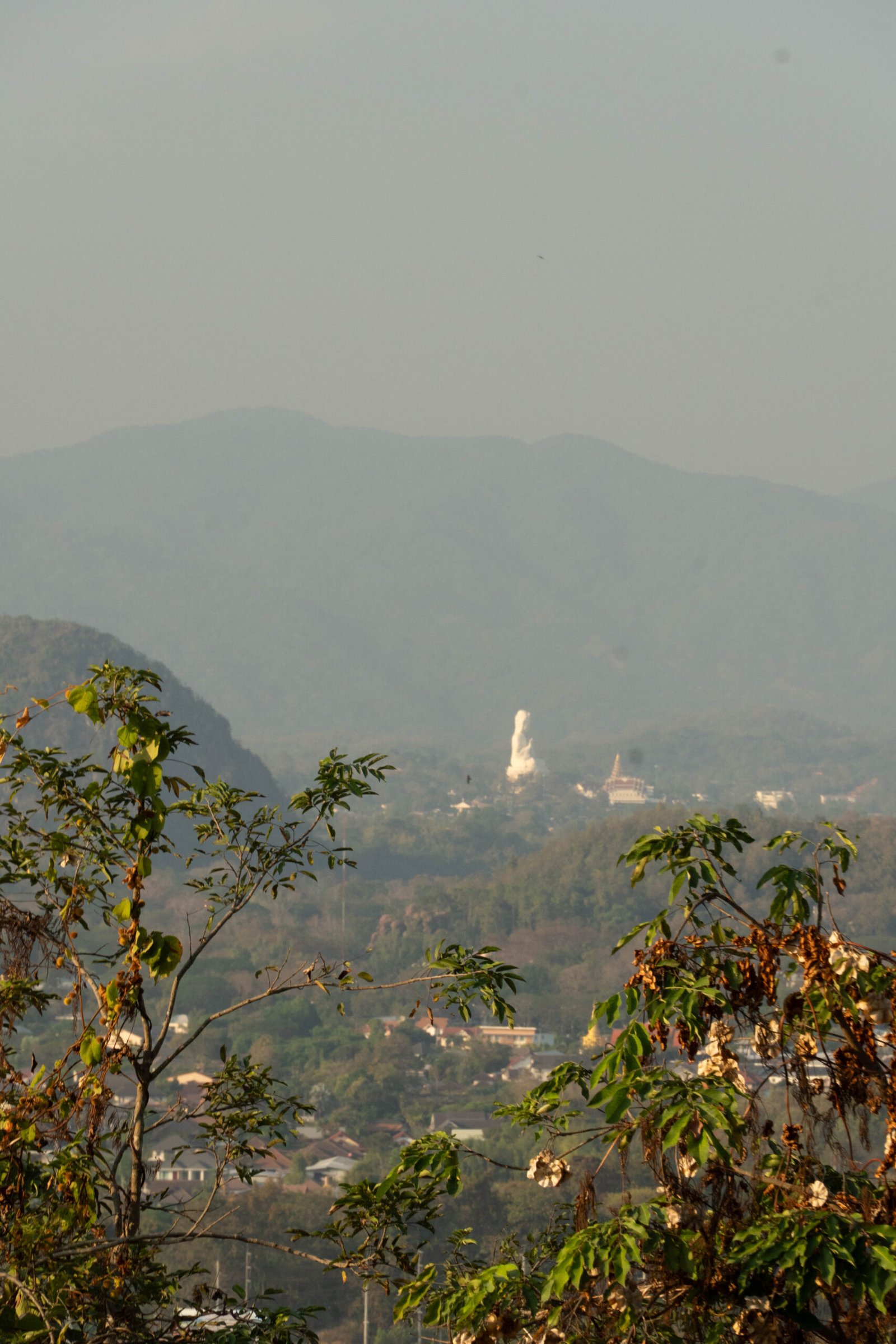 Widok z tarasu Wat Phrathat Doi Khao Kwai w Chiang Rai na biały posąg Guan Yin i panoramę miasta