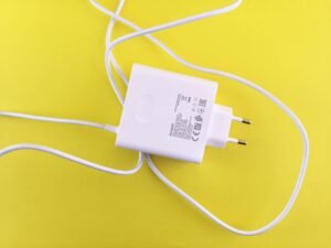 White USB charger with cable on a vibrant yellow surface, highlighting tech accessory design.