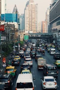 A bustling urban street with heavy traffic and towering skyscrapers in the background.